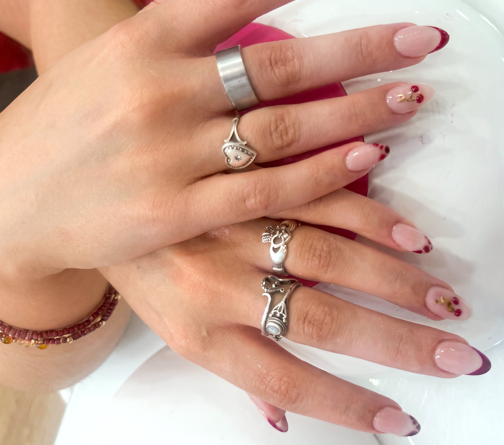 Manos con manicura natural y varios anillos decorativos.